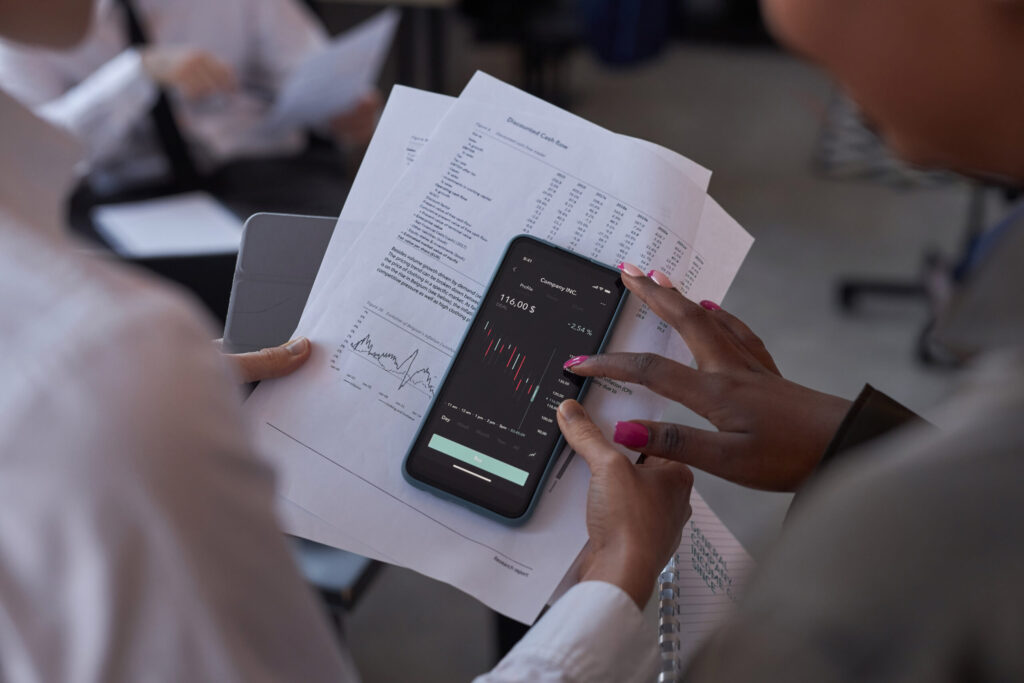 Colleagues examining financial graphs on smartphone